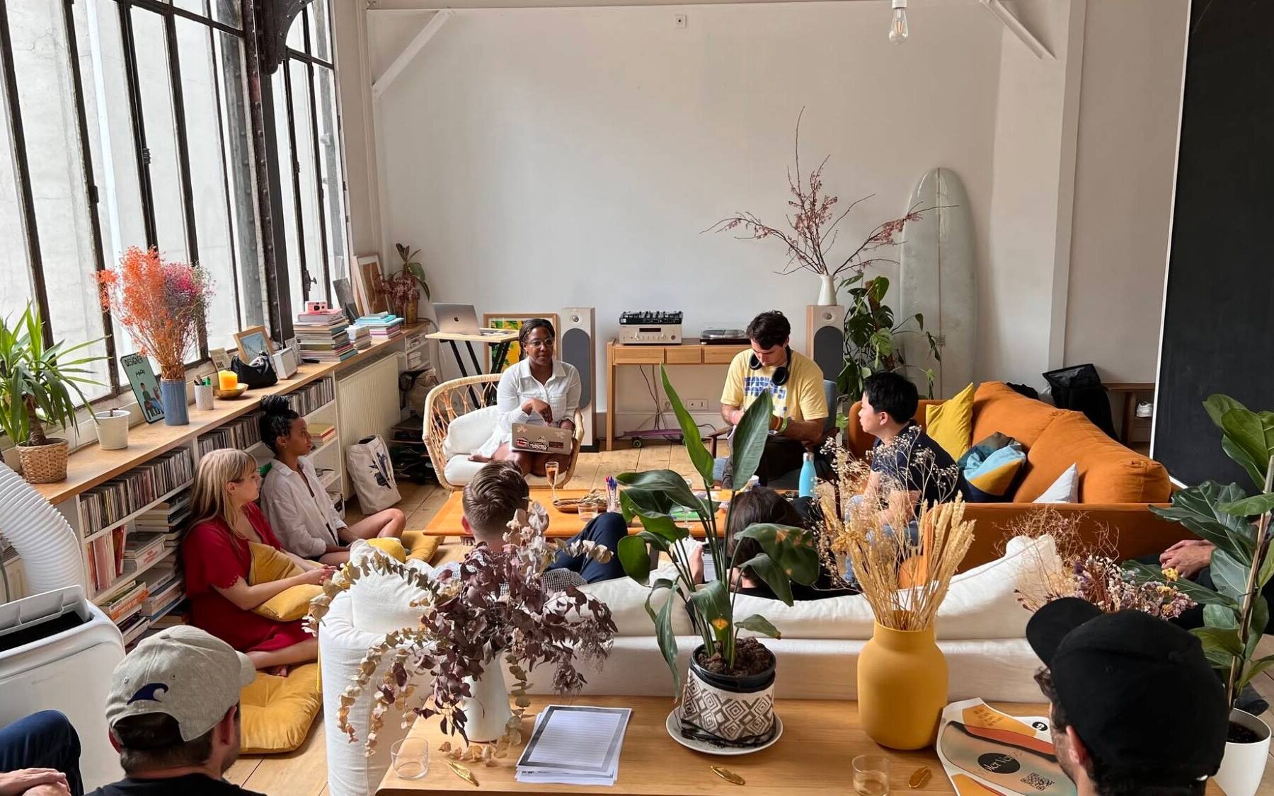 Melissa leading a small-group session in a sunlit loft, with participants on sofas and floor cushions