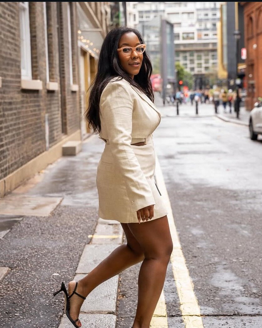 Melissa Henderson in a cream blazer dress, walking along a city street