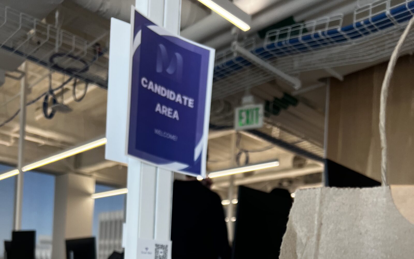 A Mercor “Candidate Area” sign above desks in an open-plan office